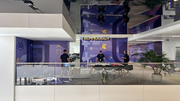 Custom wall graphics displayed across the walls of a modern technology-focused commercial interior.