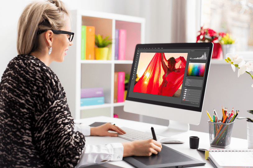 A woman in an office editing her design for a large format print on Photoshop, on her PC.